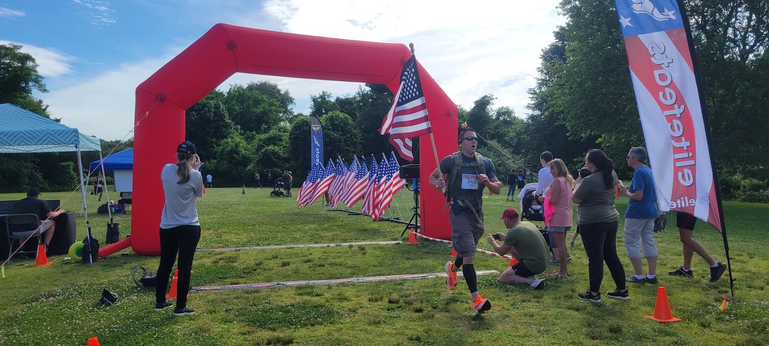 Gregory Waxman finishes the 2.2-mile run holding an American flag.
